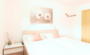 Ein Schlafzimmer mit einem Bett, einem Nachttisch und einem an der Wand hängenden Bild.