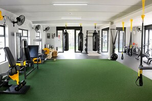 Et fitnessrum med grøn gulvbelægning, forskellig træningsudstyr og store vinduer.