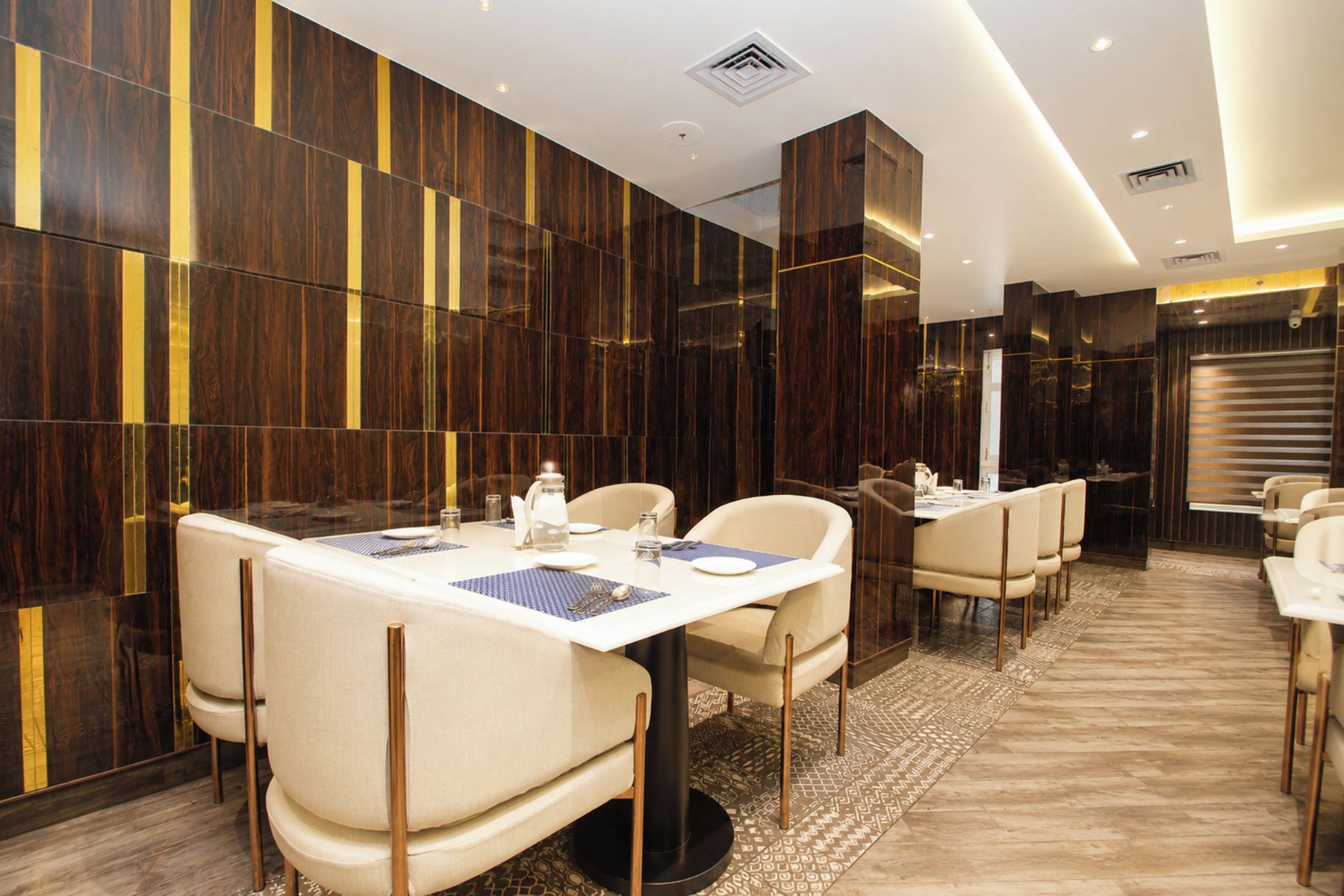 A modern dining area with a long table, multiple chairs, and a patterned rug.