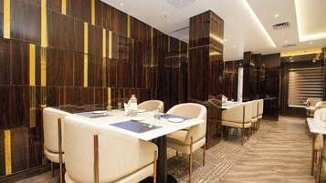 A modern dining area with a long table, multiple chairs, and a patterned rug.