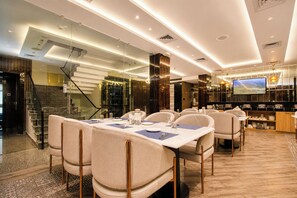 A modern dining area with a long table, multiple chairs, and a television screen. - Hotel Greeno's (Gangtok)