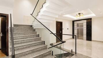 A modern interior with a marble staircase, a glass railing, and a sleek elevator.