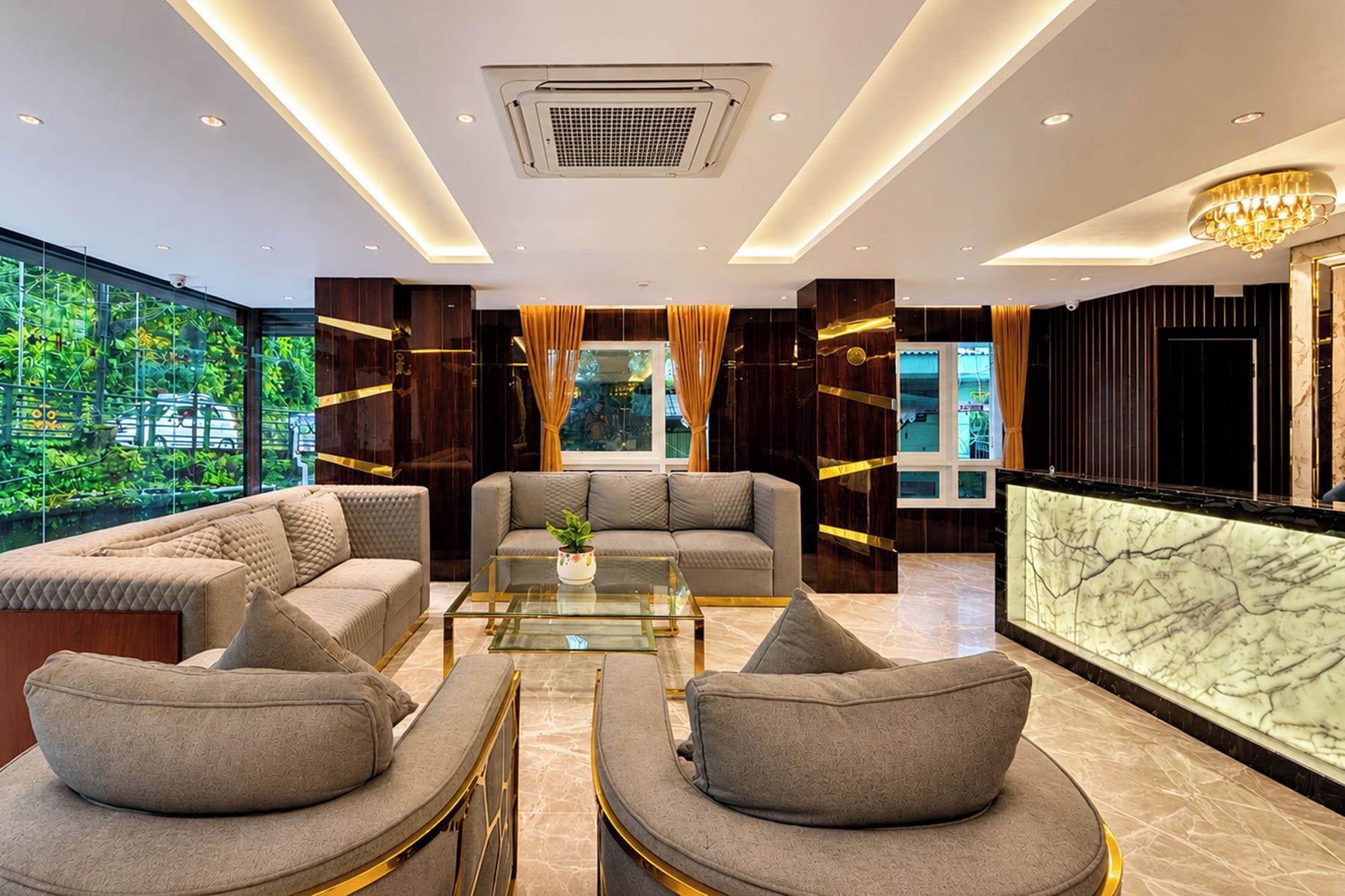 A modern living room with a glass coffee table, sofas, and a view of greenery outside.