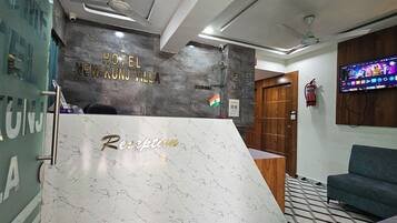 A reception desk with a marble top and the words 'Reception' and 'Hotel New Kunj Villa' on the wall behind it.