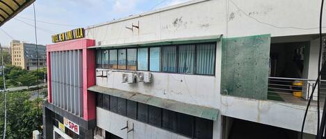 Un edificio con un cartel que dice 'Hotel New Kunj Villa' y una unidad de aire acondicionado en la fachada.