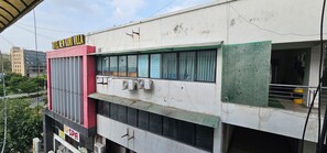 A building with a sign for 'Hotel New Kunj Villa' and an air conditioning unit on the facade.