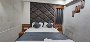 A narrow room with a bed, a headboard, and a window with curtains.