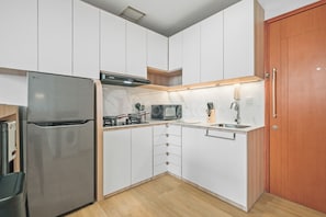 A compact kitchen with a built-in LG refrigerator, a microwave, and a sink. - Niren by Kozystay - Kuningan (South Jakarta)