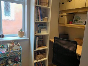 Una habitació amb finestra, una prestatgeria, un escriptori i una cadira.