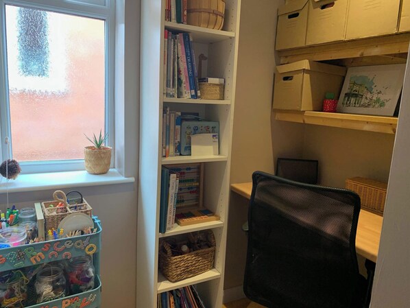Une pièce avec une fenêtre, une bibliothèque, un bureau et une chaise.