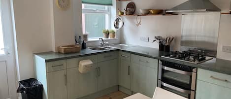 A kitchen with a sink, stove, oven, and a window with blinds.