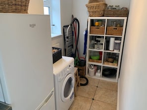 A laundry area with a washing machine, a drying rack, and a storage unit with baskets and containers. - One bedroom House close to Train station (Somerset)
