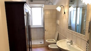 Kylpyhuone, jossa on suihku, kaksi wc:tä, pesuallas ja peili.