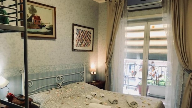 Hotellihuone, jossa on sänky, taulu, ikkuna verhoineen ja parveke, josta on näkymä.