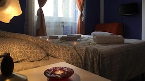 Hotellihuone, jossa on sänky, työpöytä lampun kanssa, televisio ja ikkuna, jossa on verhot.