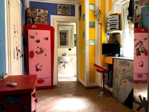 Una habitación con un armario rosa, un lavabo, un espejo y una silla roja.
