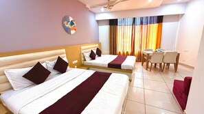 A hotel room with two beds, a dining table, chairs, a ceiling fan, and a view of the outside through curtains. - Hotel Skyla (Zirakpur)