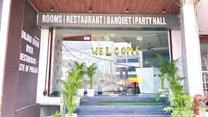 A building entrance with a sign indicating it houses rooms, a restaurant, a banquet hall, and a party hall. - Hotel Skyla (Zirakpur)