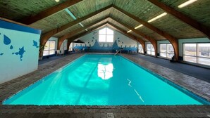 An indoor swimming pool with a high ceiling and wooden beams, surrounded by walls with a mural. - Spacious 35 Standard Double Rooms hotel in Presque Isle.Me with fitness room. (Presque Isle)