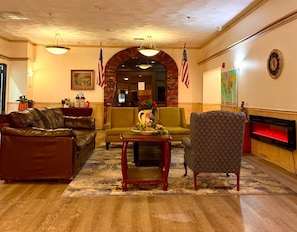 Un hall con sofás de cuero, un sillón estampado, una mesa de centro y una chimenea.
