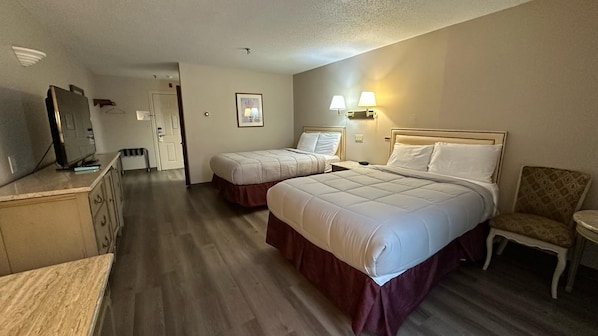 Habitació d'hotel amb dos llits, televisió, escriptori i una cadira.
