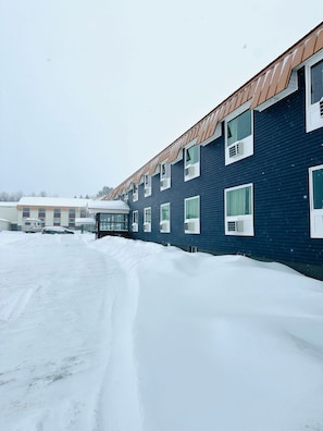 Un edificio con múltiples ventanas y el suelo cubierto de nieve.