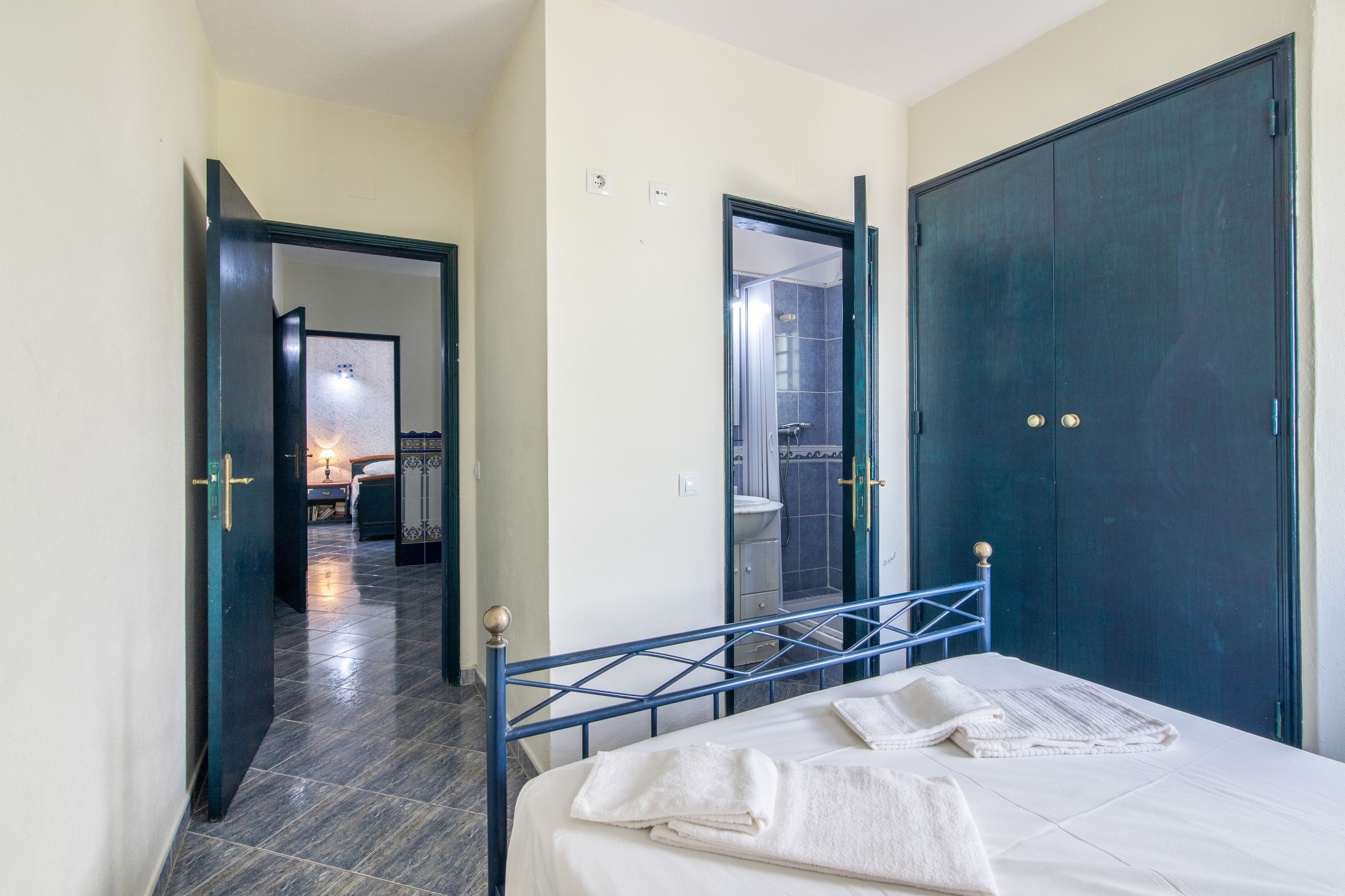Een hotelkamer met een bed, een badkamer en een gang naar een andere kamer.