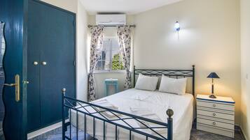 Een slaapkamer met een bed, nachtkastje, lamp en een kledingkast.