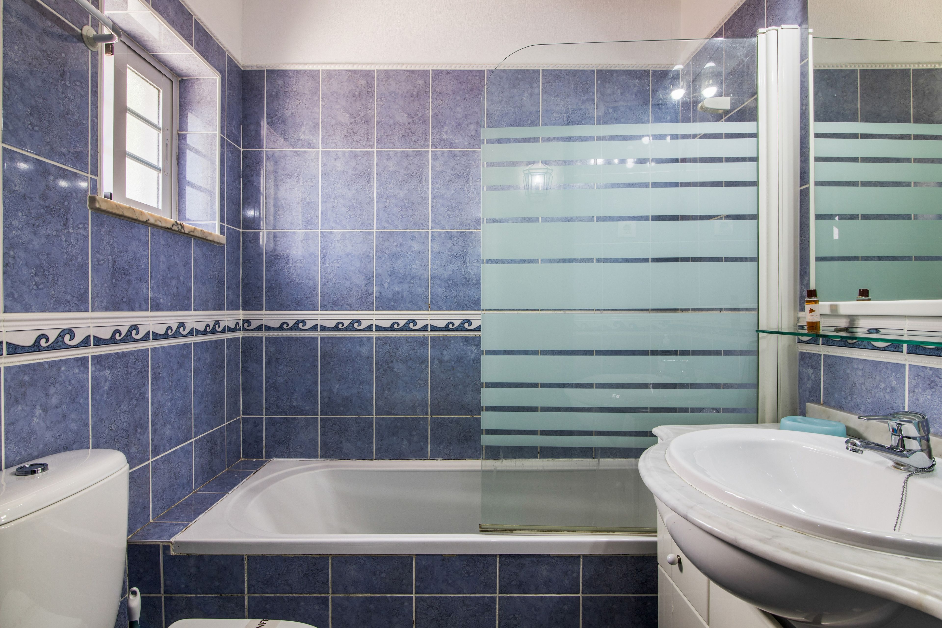 A bathroom with a bathtub, a sink, and a mirror.