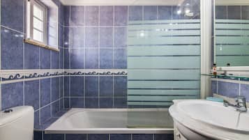 A bathroom with a bathtub, a sink, and a mirror.
