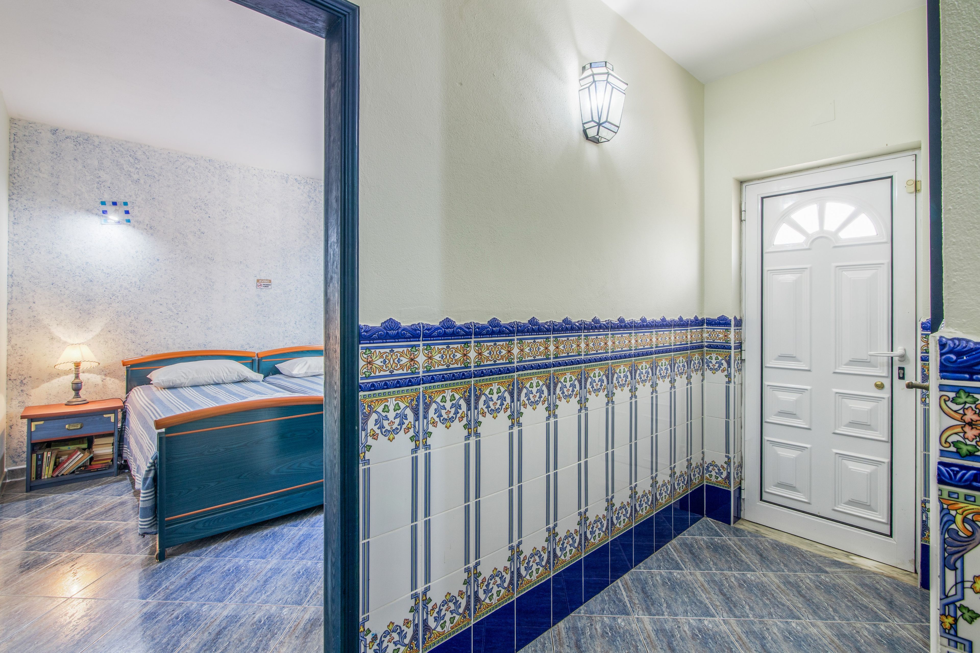 Un dormitorio con cama, mesita de noche, lámpara e iluminación en la pared.