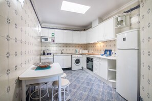 A compact kitchen with a washing machine, microwave, and a coffee maker.