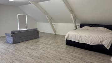 A room with a bed, a sofa, and a window.