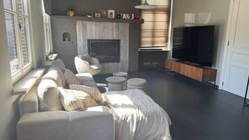 A modern living room with a fireplace, sofa, TV, and a large window.