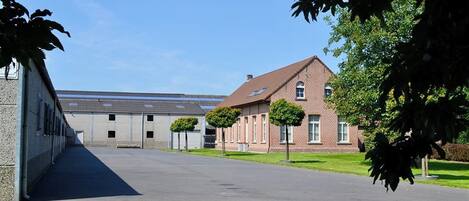 A building with a paved driveway, a brick building with a pitched roof, and a clear sky.