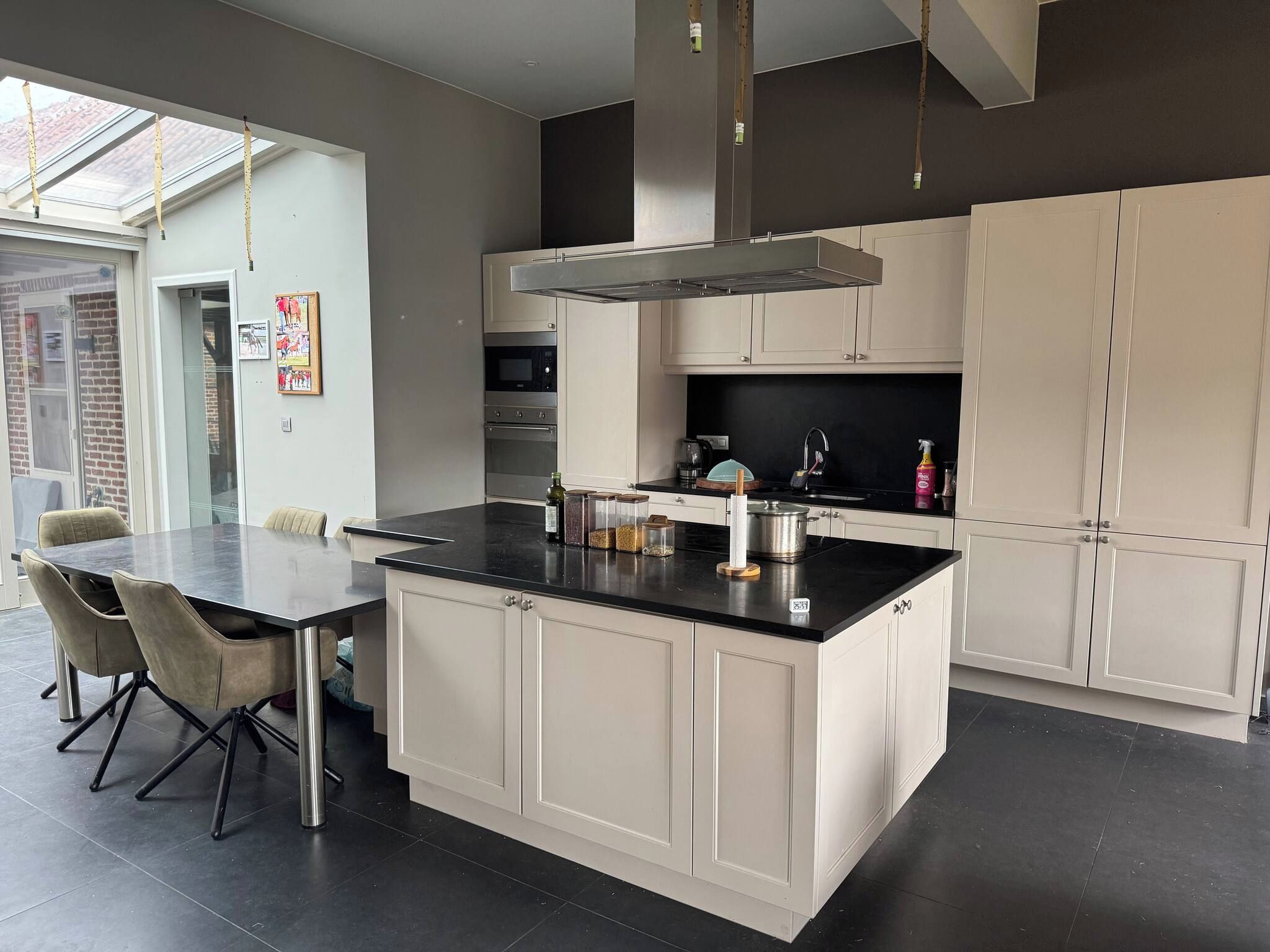 A modern kitchen with a central island, white cabinetry, and a dining area with a table and chairs.