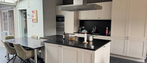 A modern kitchen with a central island, white cabinetry, and a dining area with a table and chairs.