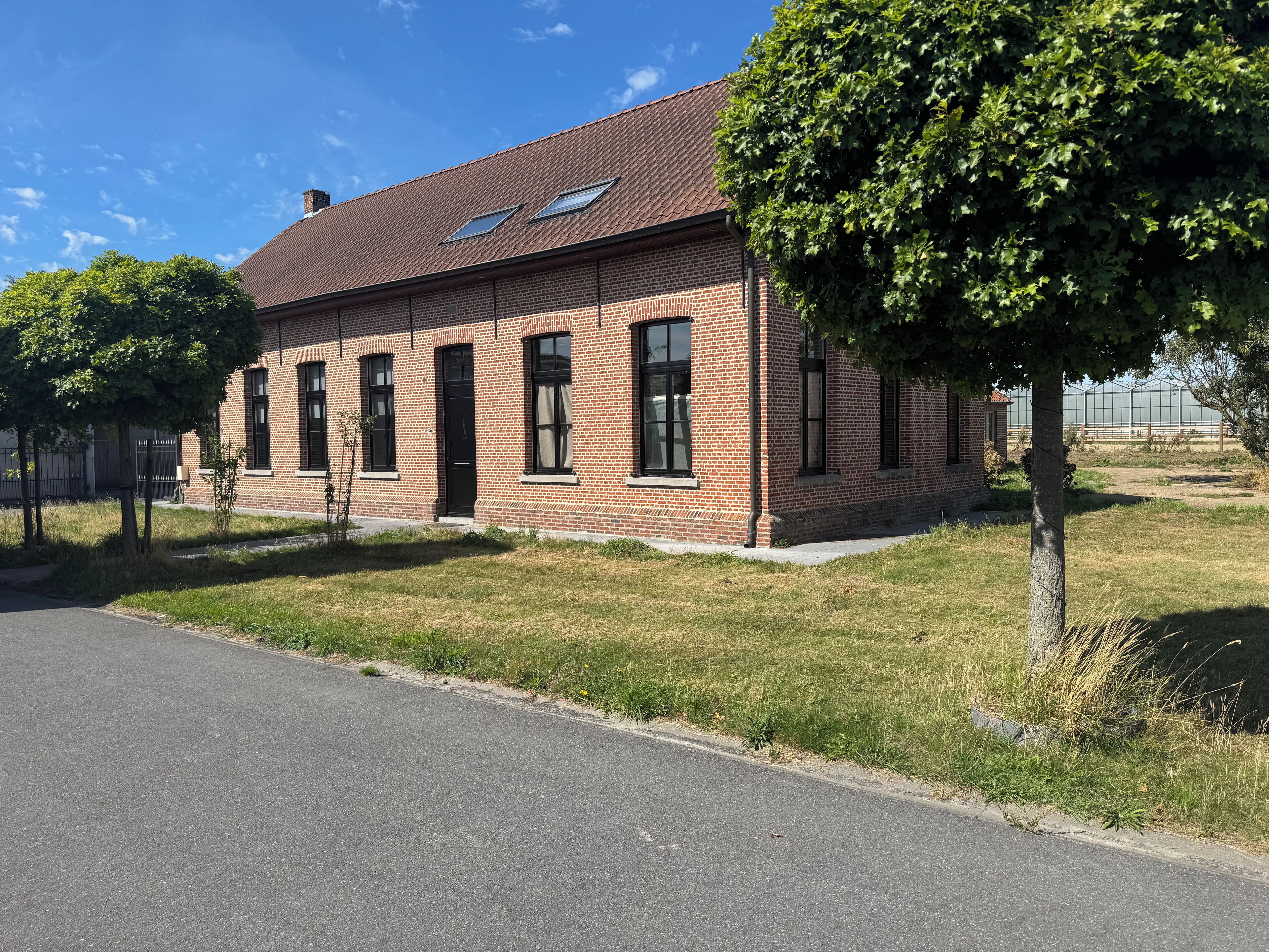 A brick building with a flat roof, multiple windows, and a paved driveway.