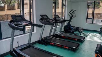 Un gimnasio con cintas de correr, bicicletas estáticas y suelo verde.