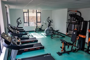 Un gimnasio con cintas de correr, bicicletas estáticas y equipo de levantamiento de pesas.