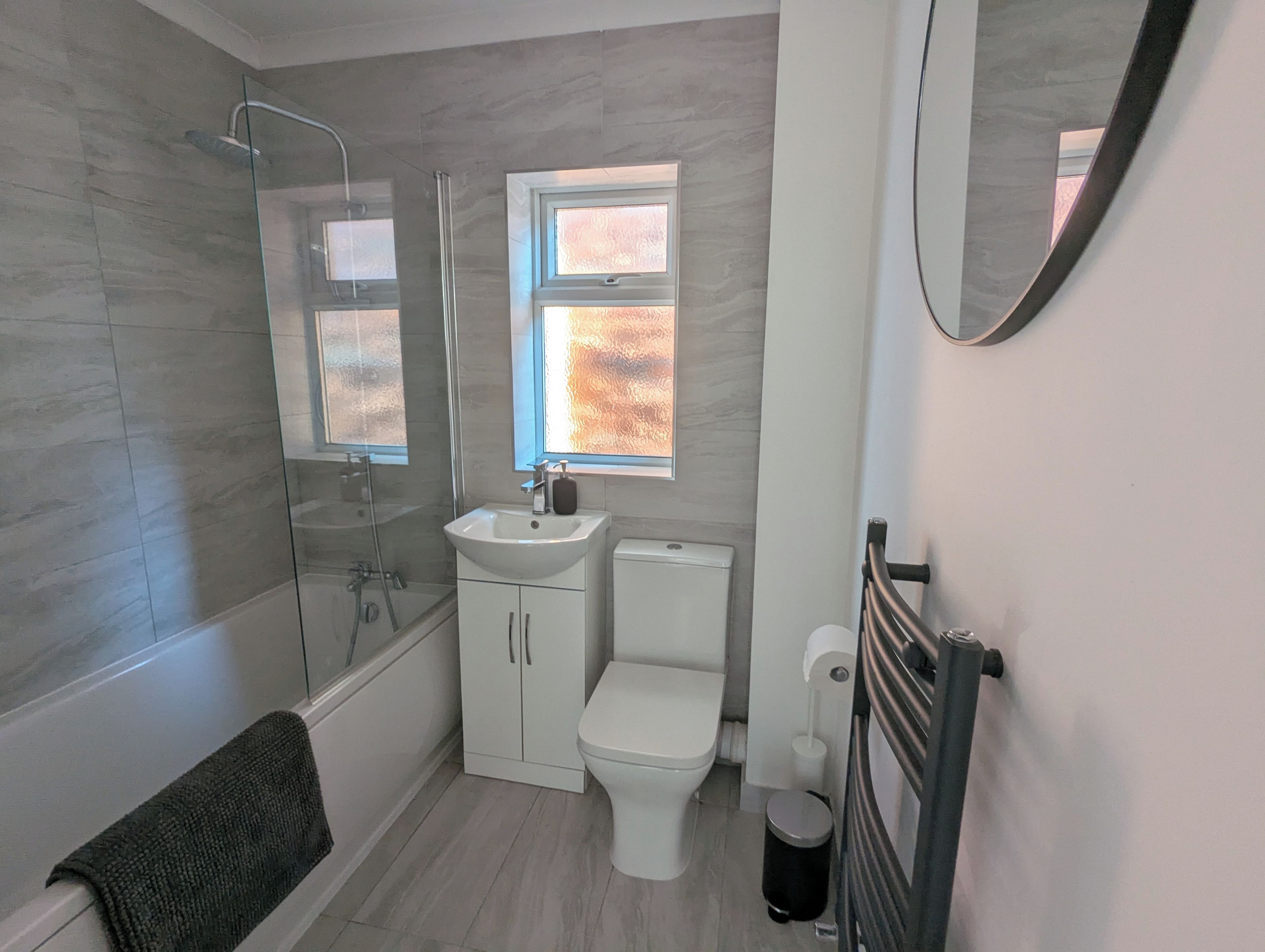 A modern bathroom with a glass shower enclosure, a white sink, a toilet, and a towel rack.