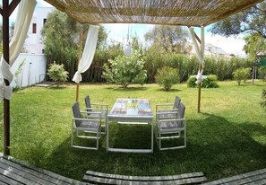 An outdoor patio with a table and chairs, surrounded by a grassy area and various plants. - Casa Montecote Playa – Beach House Near Caños de Meca & Trafalgar (Barbate)