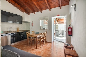 A compact kitchen with modern appliances, a dining area with wooden furniture, and a visible emergency exit sign.