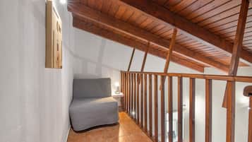 Een balkon met een houten hekwerk, een fauteuil met kussens en een wandlamp.