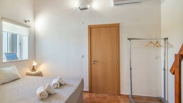 Une chambre à coucher avec un lit, une porte en bois, un porte-serviettes et une fenêtre.