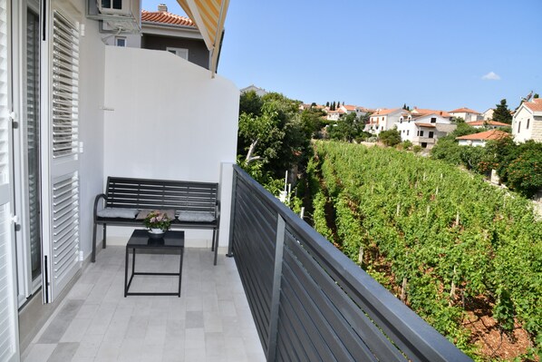 Un balcon avec un banc et une table, donnant sur un vignoble.