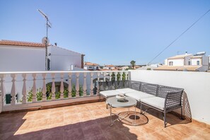A terrace with a white sofa, a round table, and a decorative fence.