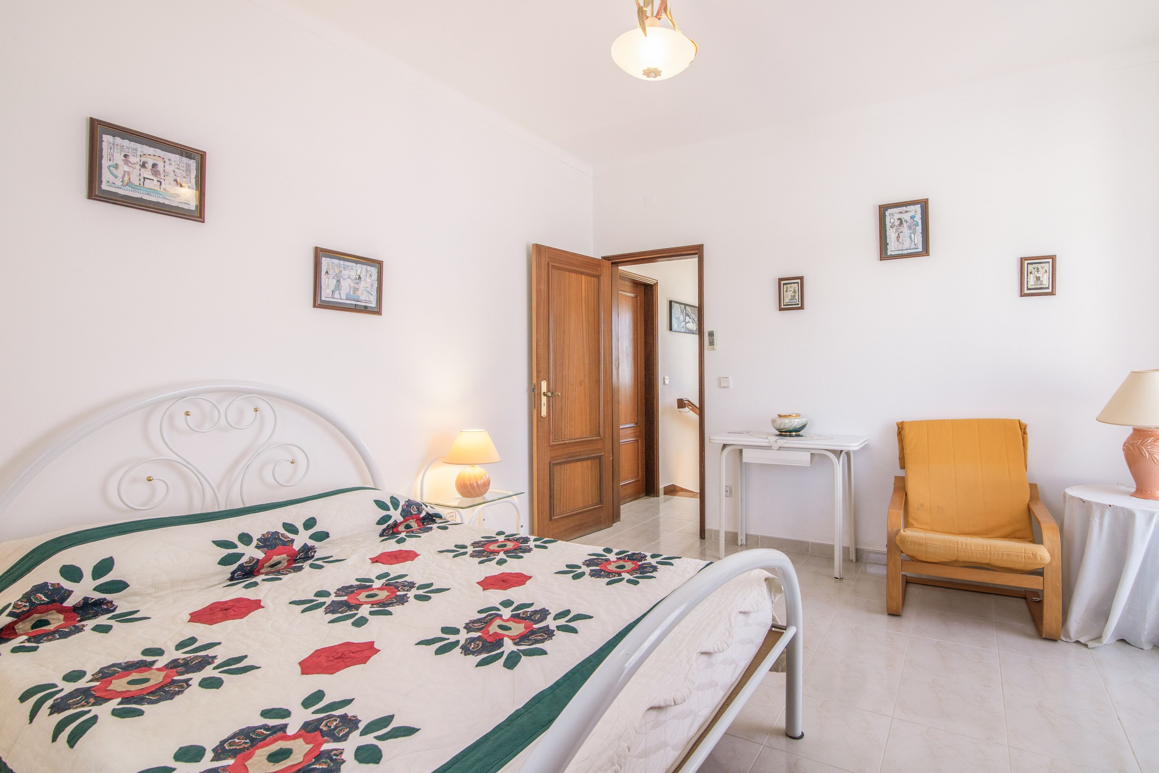 Un dormitorio con cama, una silla, una mesa y una puerta.