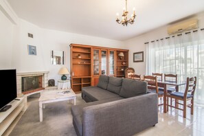 A living room with a sofa, TV, fireplace, wooden cabinet, and dining table.