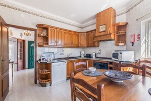A kitchen with wooden cabinets, a dining table with chairs, a microwave, and a coffee maker.